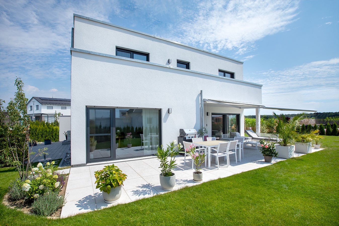 Modernes-effizienzhaus-mit-flachdach-außenansicht-garten-terrasse-fertighaus