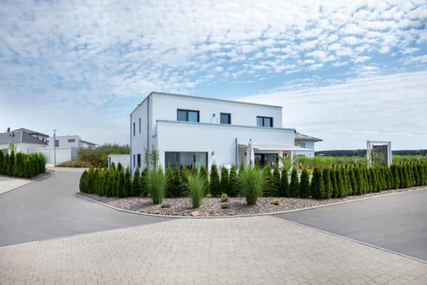 Modernes-effizienzhaus-mit-flachdach-außenansicht-straße-hecke-fertighaus