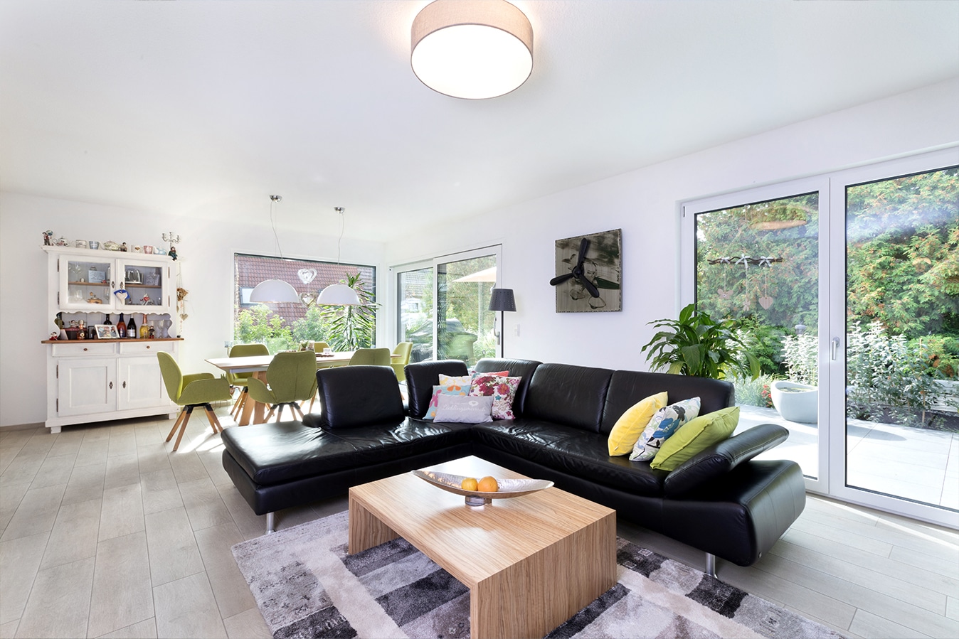 Walmdachbungalow-offener-wohn-essbereich-mit-schwarzem-sofa